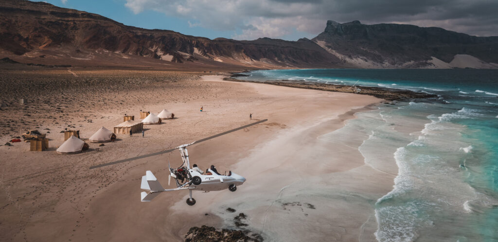 Gyrocopter flying over beach camp in Socotra