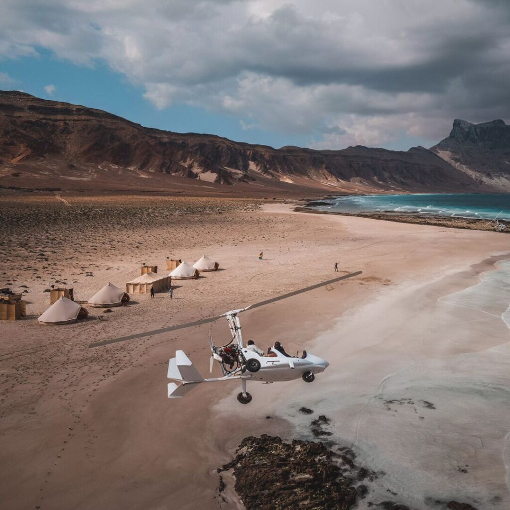 Gyrocopter flying over beach camp in Socotra