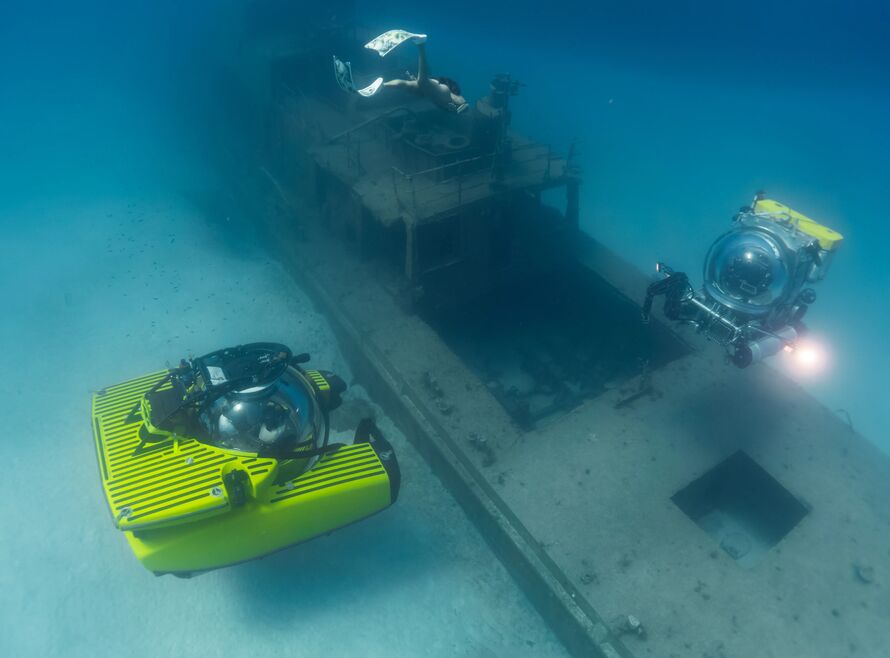 Freediver diving on a wreck with two submersibles in the Mediterranean