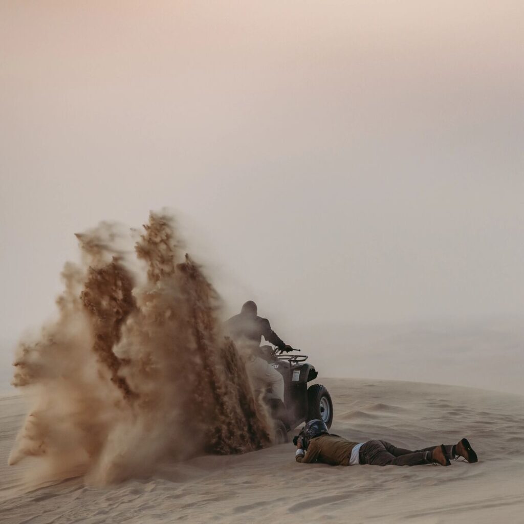 Photographer on the floor shooting ATV with sand being moved