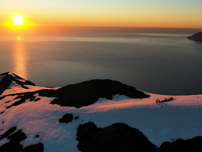 Drone shot of group on mountaintop and Midnight Sun