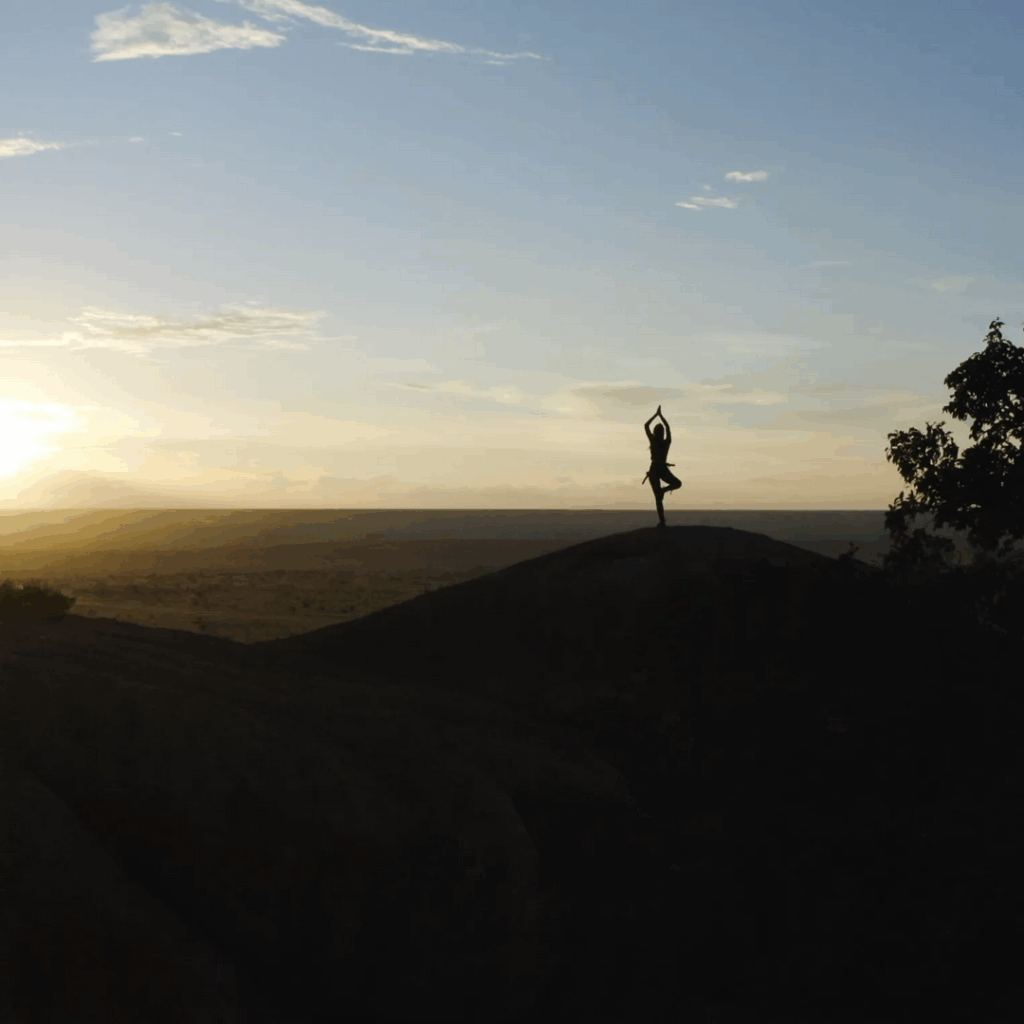 Person doing yoga during sunset in the distance