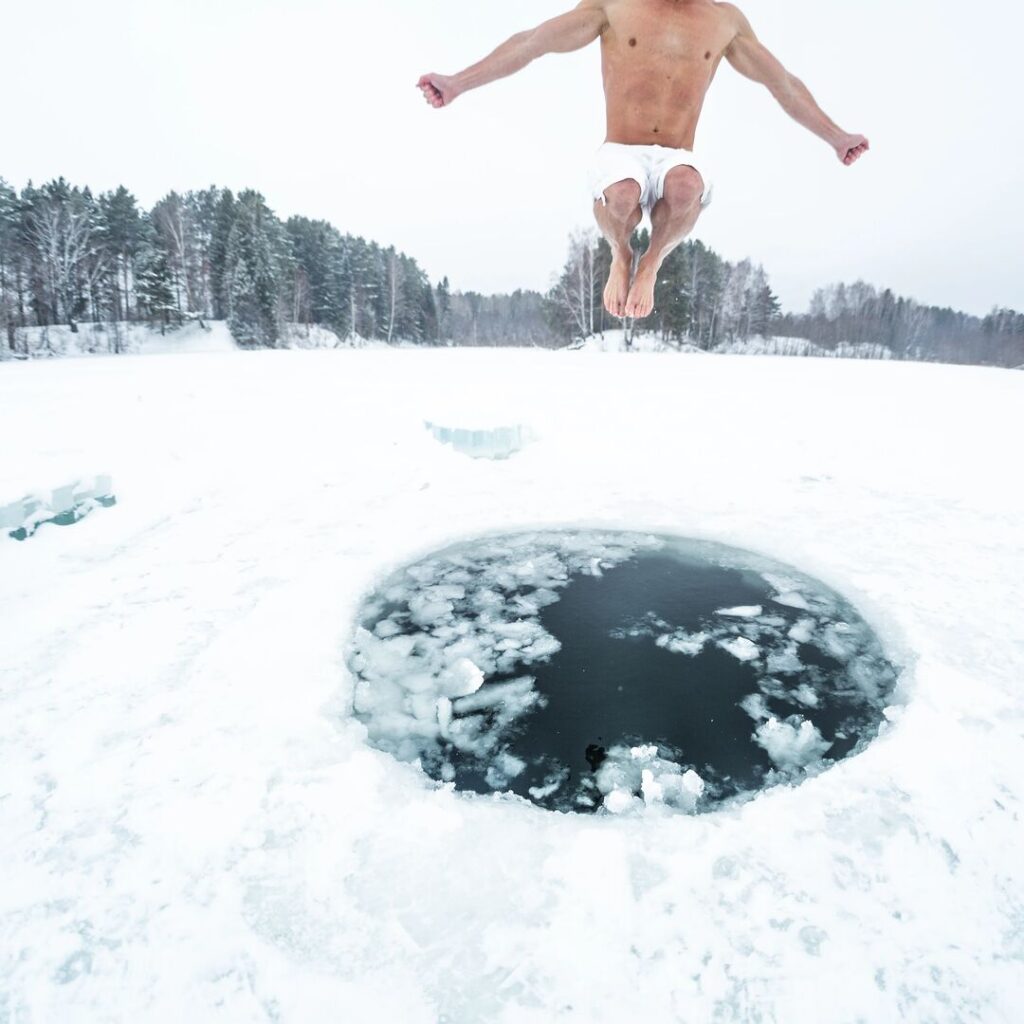 Person jumping into an ice plunge carved into the ice sheet