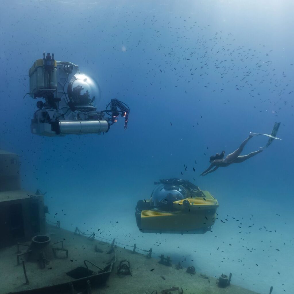 Two submersibles with a freediver over a shipwreck