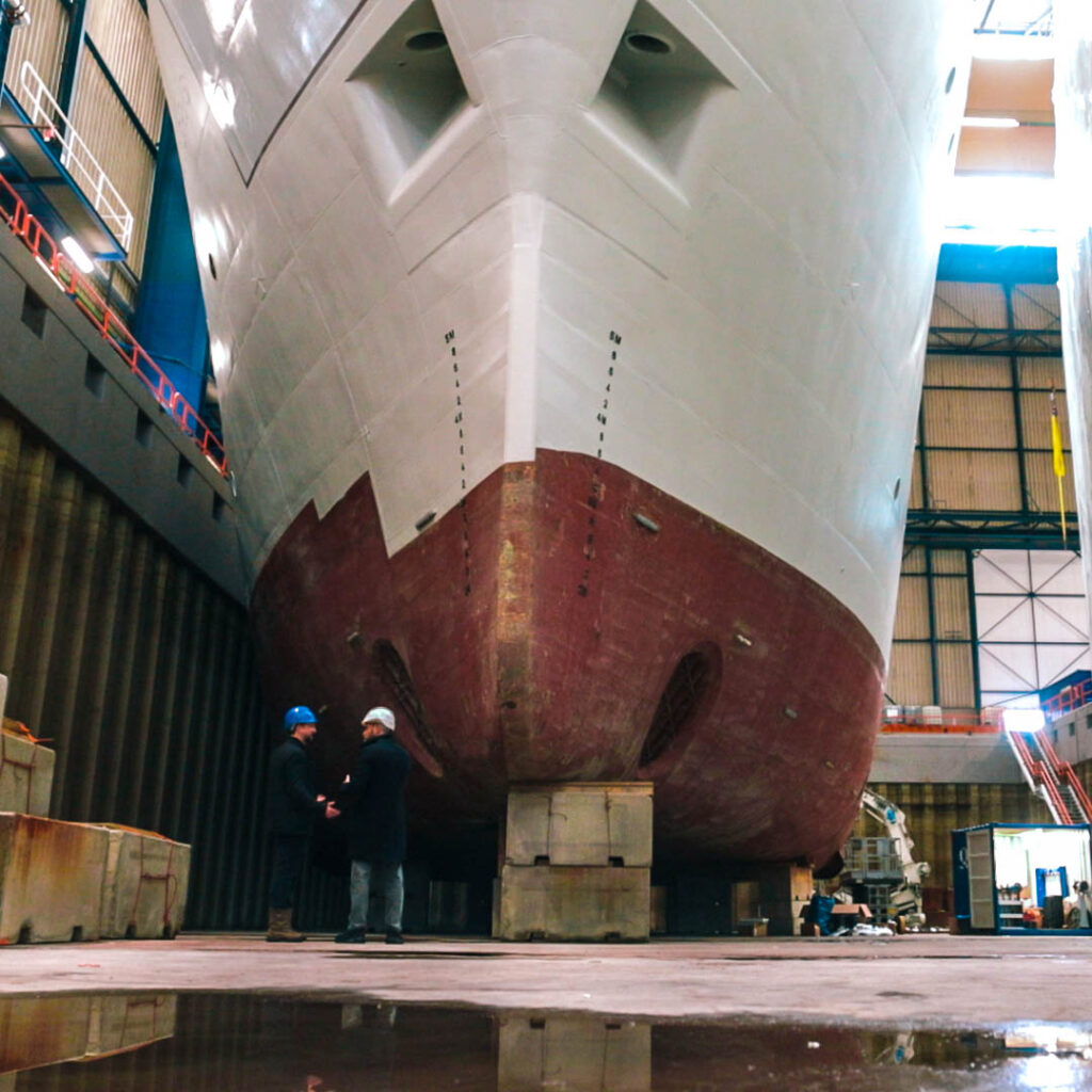 Two people inspect a yacht being built