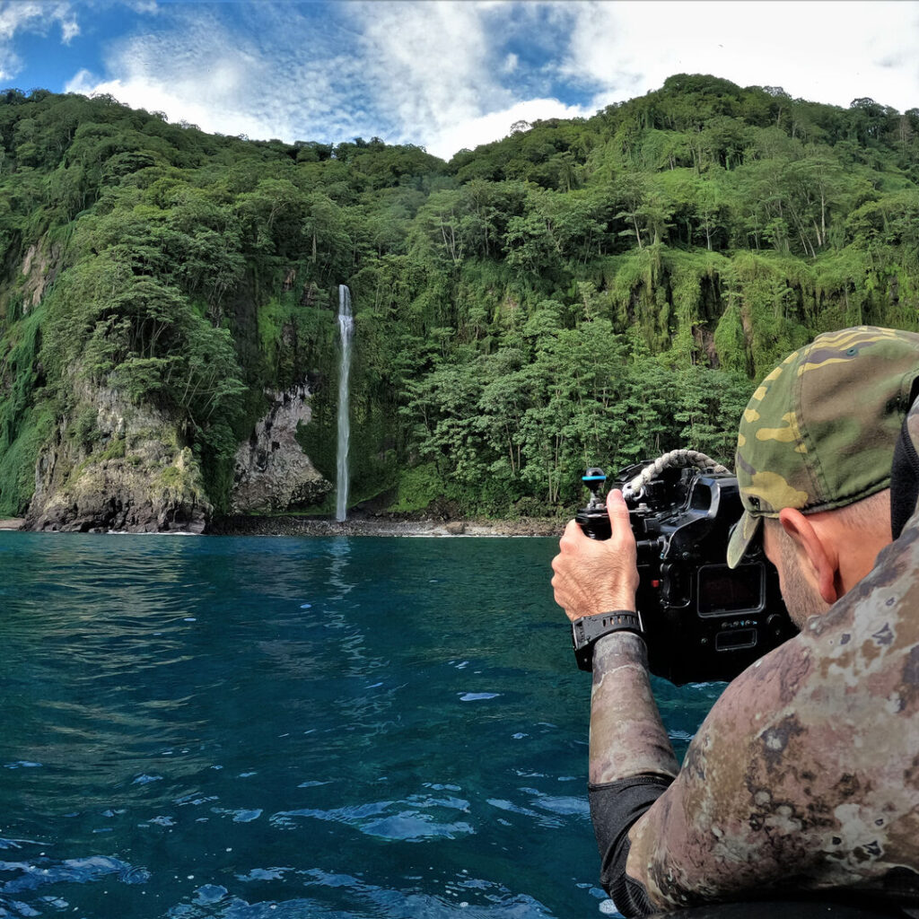 Photographer taking a photo of a waterfall on Cocos Island